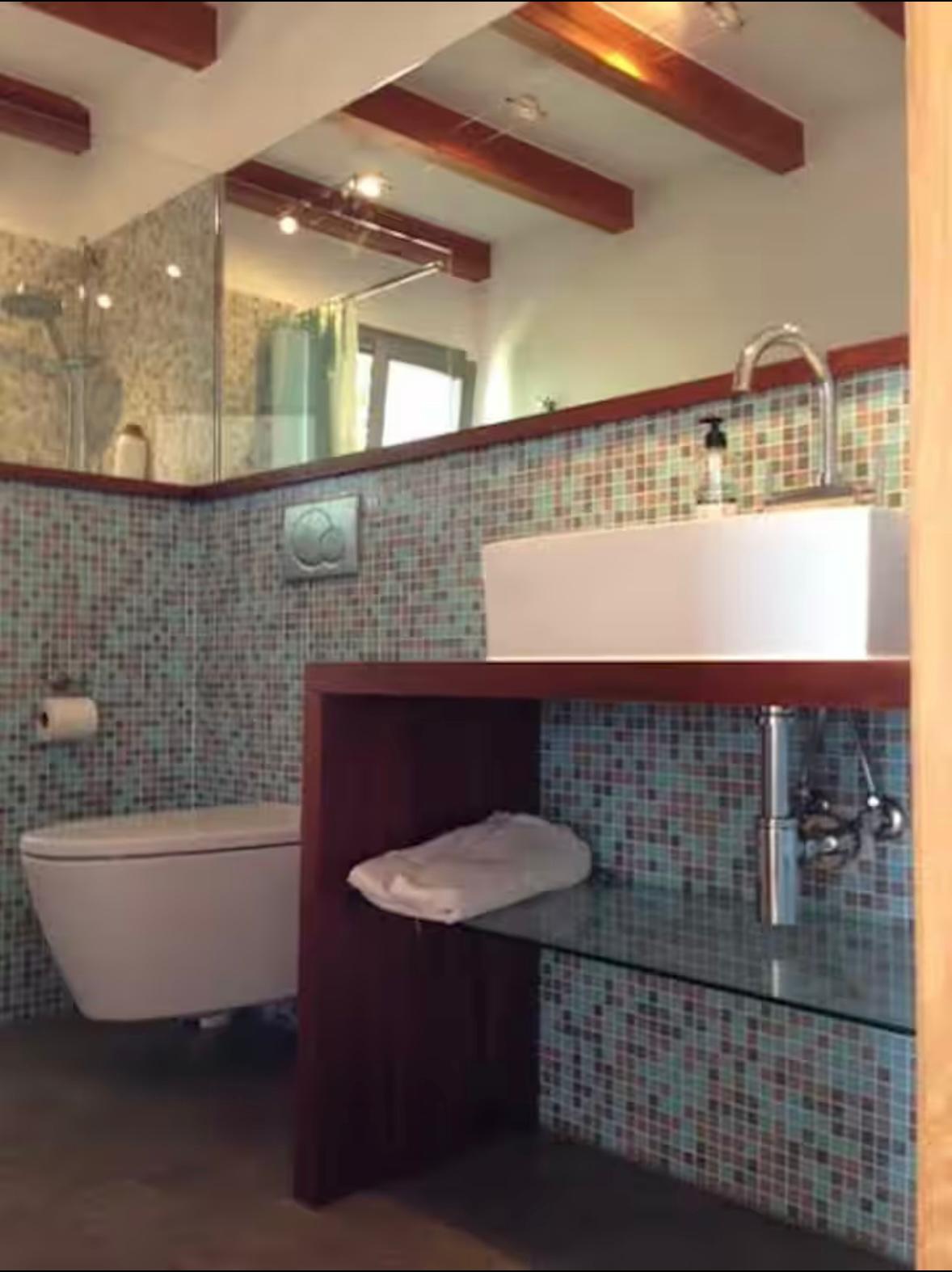 Badezimmer mit Mosaik-Fliesen und Holzbalken