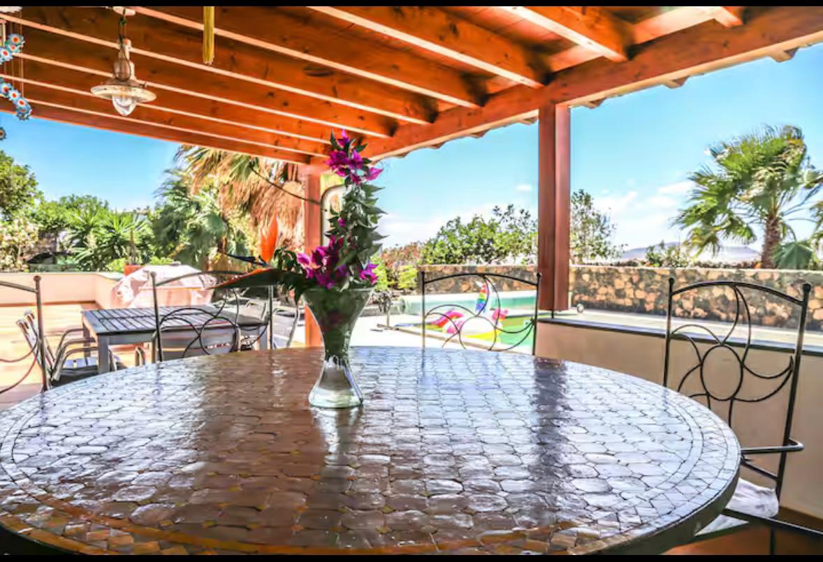 Überdachte Terrasse mit Mosaiktisch und Poolblick